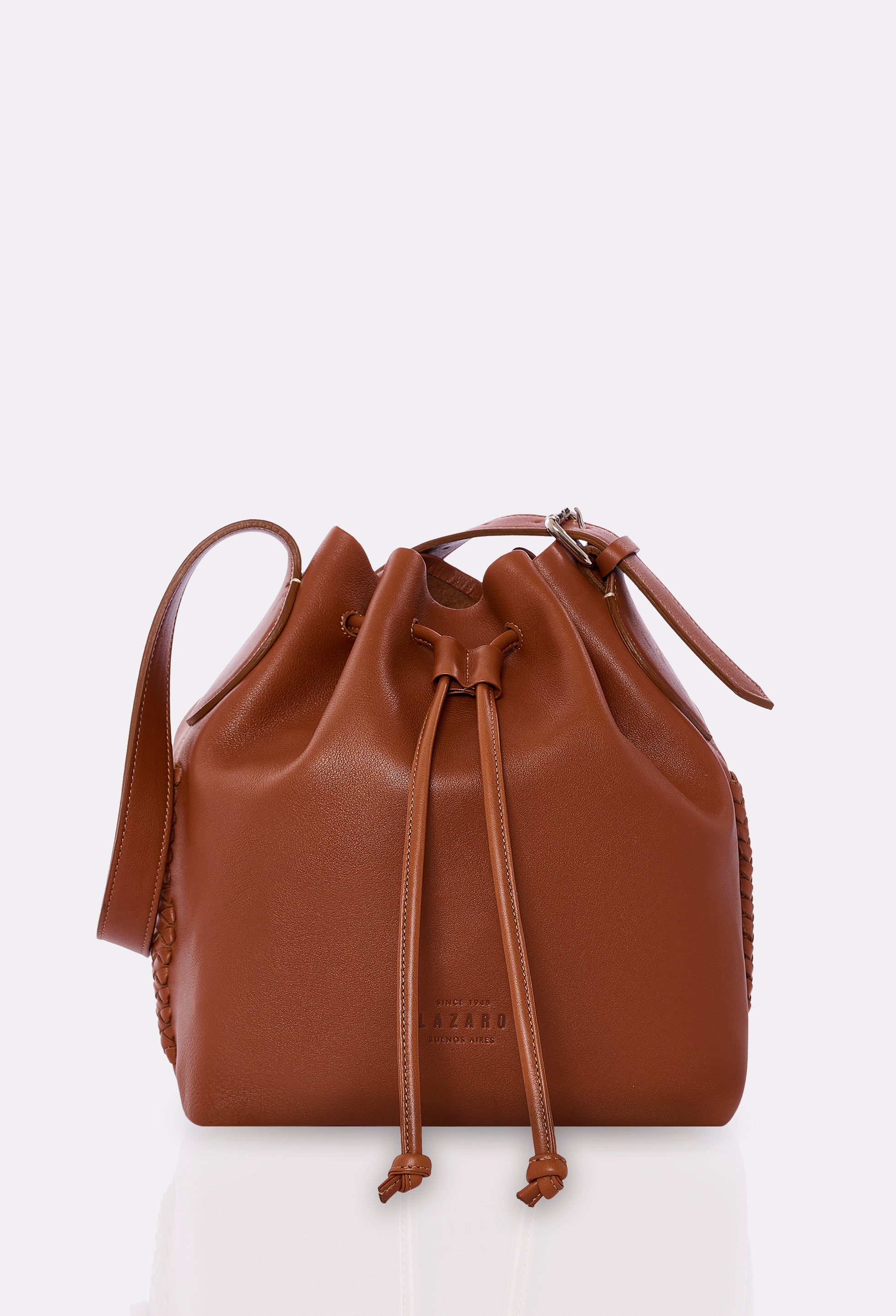 A tan leather bucket bag with a drawstring top and a front handle.