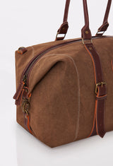 Partial photo of a Coffee Canvas Duffel Bag with leather handles, a zippered main compartment, and distressed antiqued bronze fittings.
