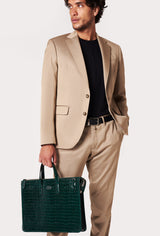 A model carries a sophisticated green croco leather slim briefcase, showcasing its sophisticated design. The bag features a detachable shoulder strap, adding to its elegant appeal. The model confidently displays the bag's size and craftsmanship while exuding a sense of style and elegance.