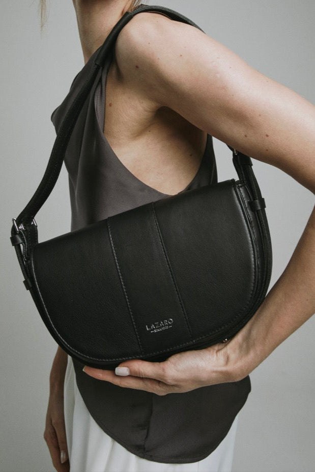 Woman holding a black leather bag against a neutral background