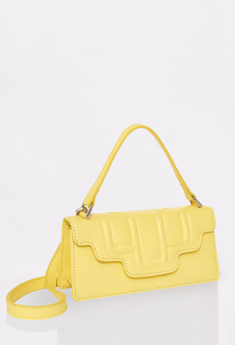 Side of a Yellow Leather Crossbody Flap Bag Hilda with a raised design flap, Lazaro logo and a removable and adjustable strap.