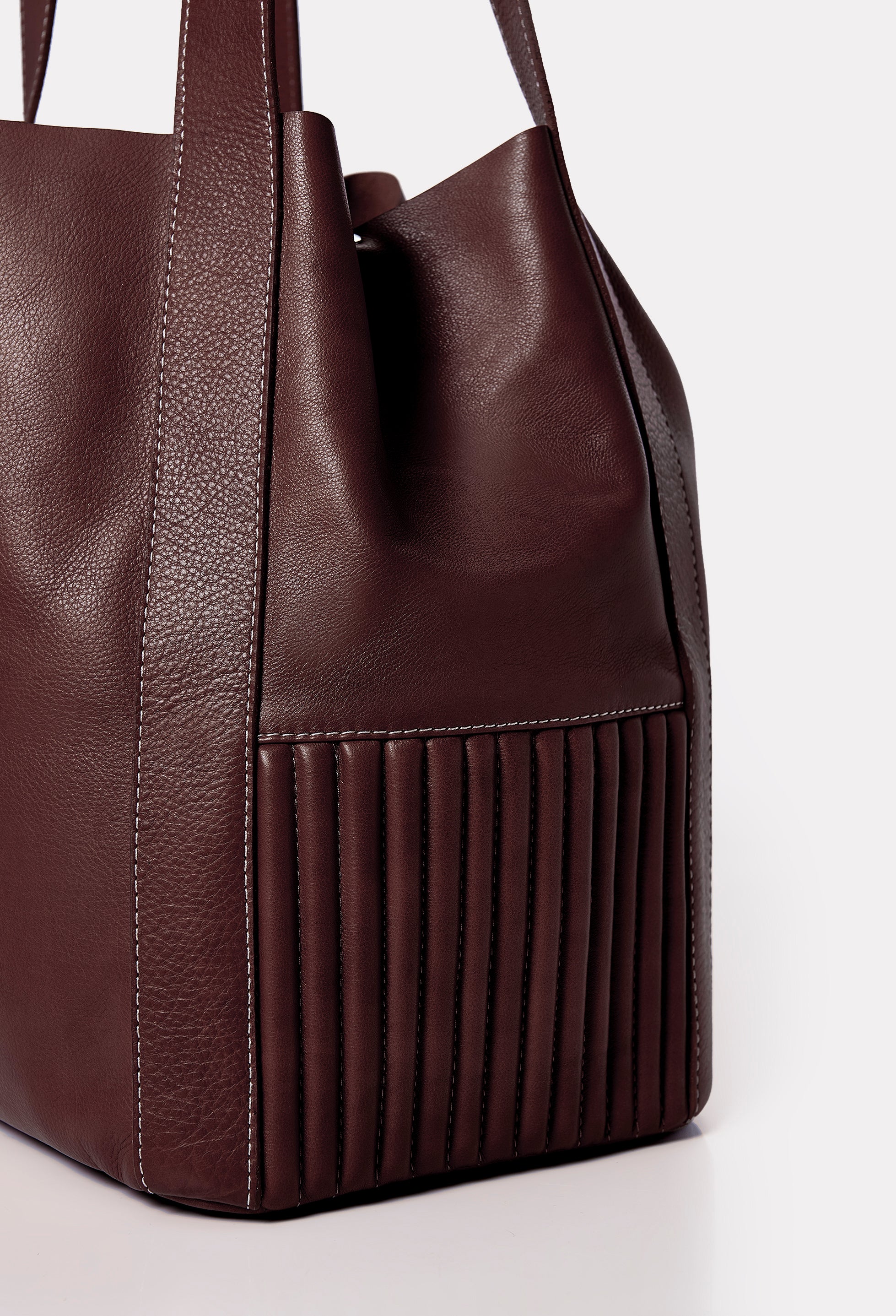 Partial photo of a Large Leather Bucket Bag Ushuaia Coffee with needlework on the sides and contrast stitching highlights.
