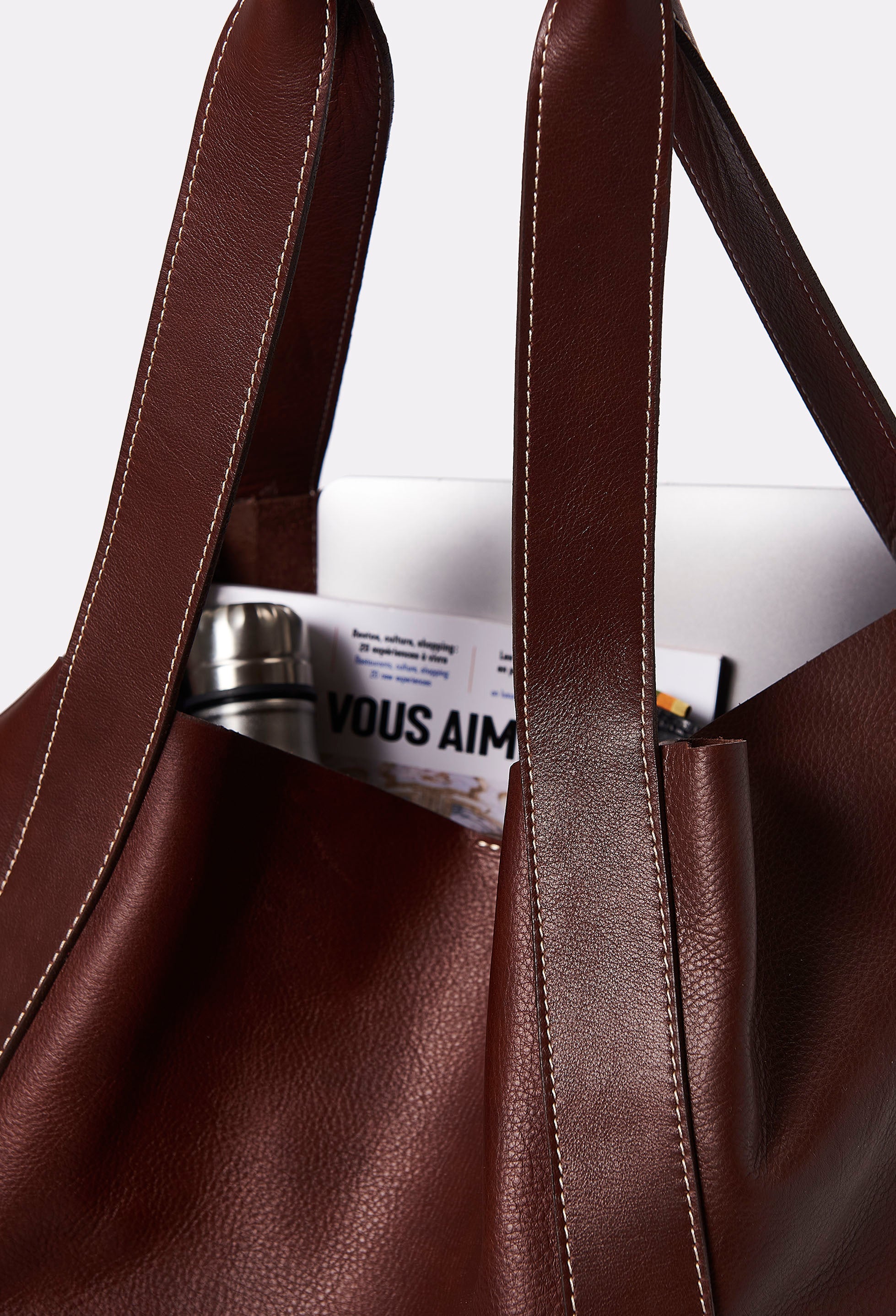 Interior of a Large Leather Bucket Bag Ushuaia Coffee that shows the bag fits a computer, a book and a water bottle.