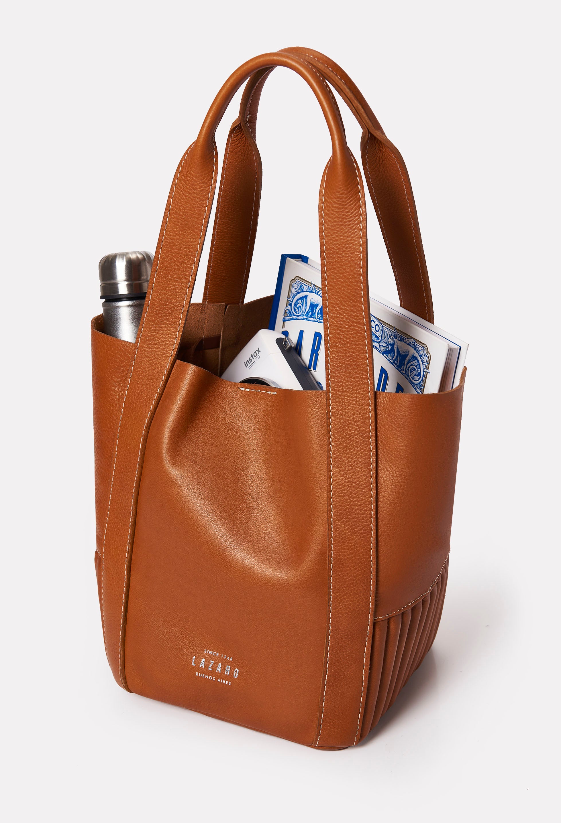 Interior of a Tan Leather Small Bucket Bag Ushuaia that shows the bag fits a magazine and a water bottle.