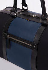 Partial photo of a Black Canvas and Leather Duffel Bag with a blue leather strap, a zippered main compartment, a zippered back pocket and leather handles.