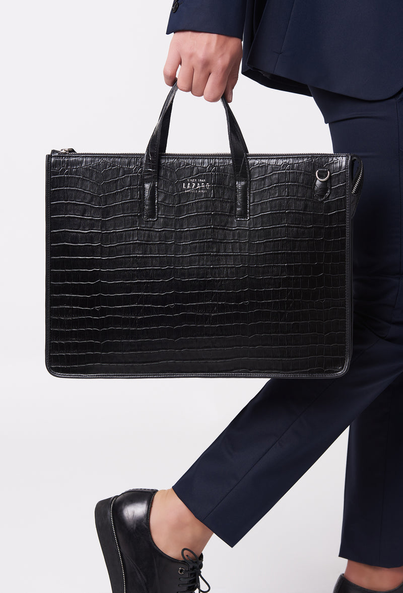 A model carries a sophisticated black croco leather slim briefcase, showcasing its sophisticated design. The bag features a detachable shoulder strap, adding to its elegant appeal. The model confidently displays the bag's size and craftsmanship while exuding a sense of style and elegance.