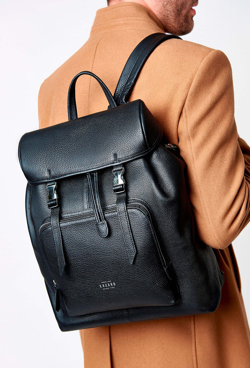 A model carries a sophisticated black large leather backpack with buckle closure, showcasing its sophisticated design. The bag features external and internal multifunctional zippered pockets, adding to its elegant appeal. The model confidently displays the bag's size and craftsmanship while exuding a sense of style and elegance.