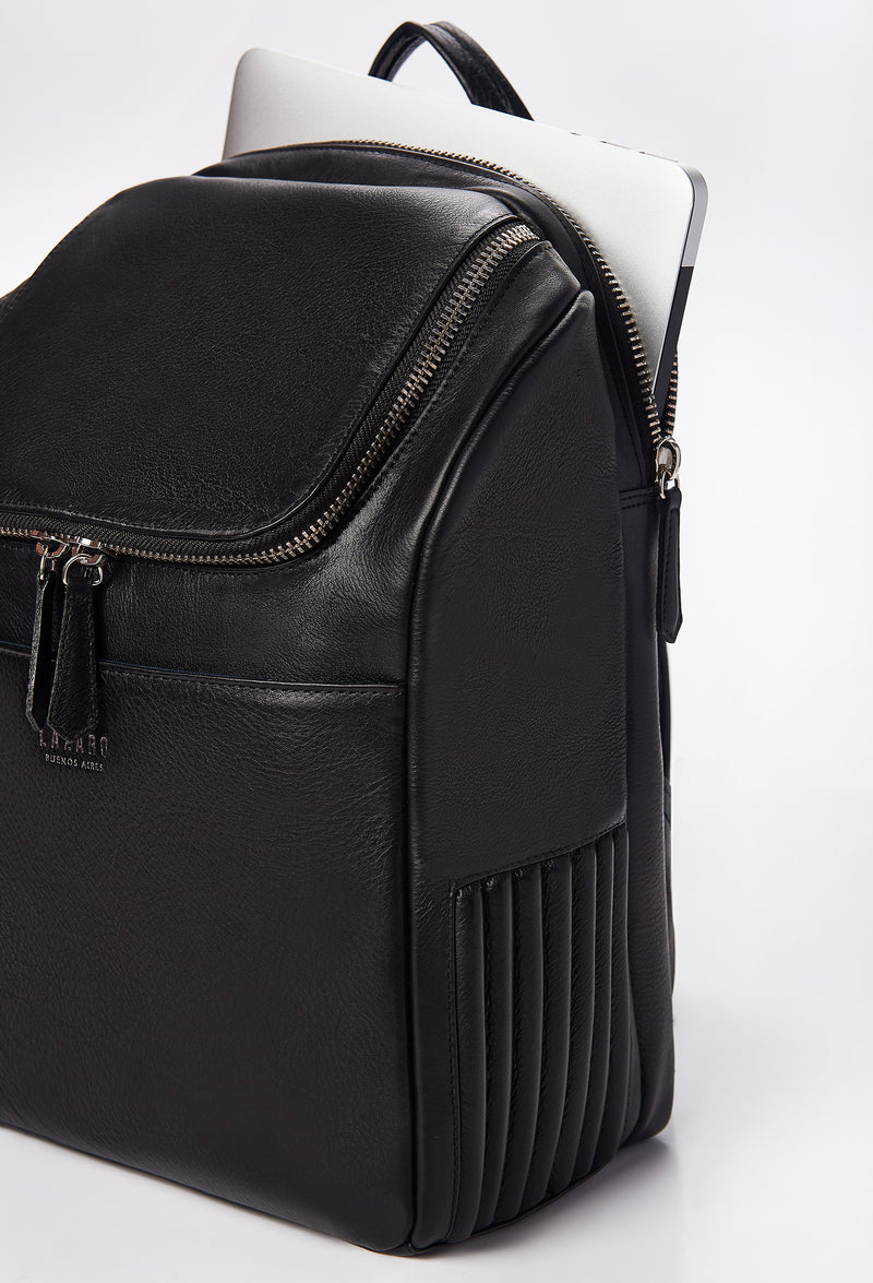 Partial photo of a Black Leather Backpack that shows a special zippered and padded compartment for a computer, side needlework, a main zippered compartment and a front multifunctional pocket.