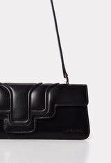 Partial photo of a Black Leather Shoulder Flap Bag Hilda with a raised design flap and Lazaro logo.