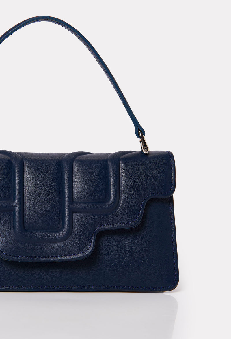 Partial photo of a Blue Leather Crossbody Flap Bag Hilda with a raised design flap and Lazaro logo.