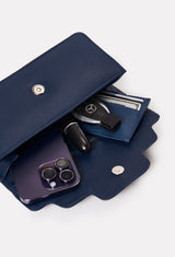 Interior of a Blue Leather Crossbody Flap Bag Hilda that shows the bag packed with a Lazaro card holder, cell phone, car keys and a lipstick.