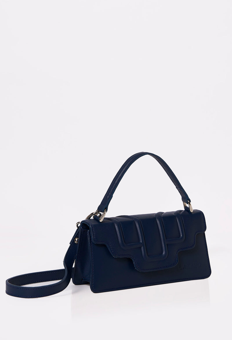 Side of a Blue Leather Crossbody Flap Bag Hilda with a raised design flap, Lazaro logo and a removable and adjustable strap.