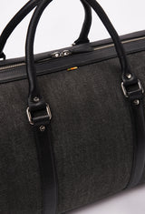 Partial photo of a Canvas Duffel Bag with a zippered main compartment, leather handles and silver ironwork.