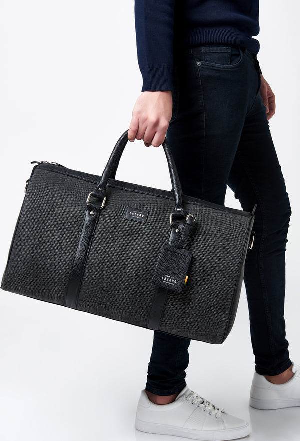 A model carries a sophisticated canvas duffel bag, showcasing its luxurious design. The bag features a leather id and leather handles, adding to its elegant appeal. The model confidently displays the bag's size and craftsmanship while exuding a sense of style and sophistication.