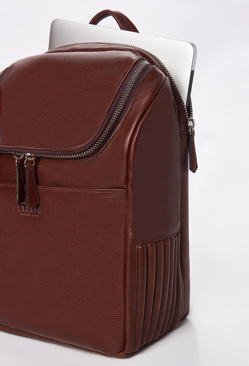 Partial photo of a Coffee Leather Backpack that shows a special zippered and padded compartment for a computer, side needlework, a main zippered compartment and a front multifunctional pocket.