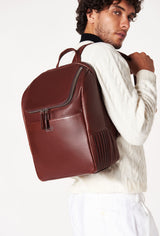 A model carries a sophisticated coffee leather backpack, showcasing its sophisticated design. The bag features unique needlework on its side, adding to its elegant appeal. The model confidently displays the bag's size and craftsmanship while exuding a sense of style and elegance.