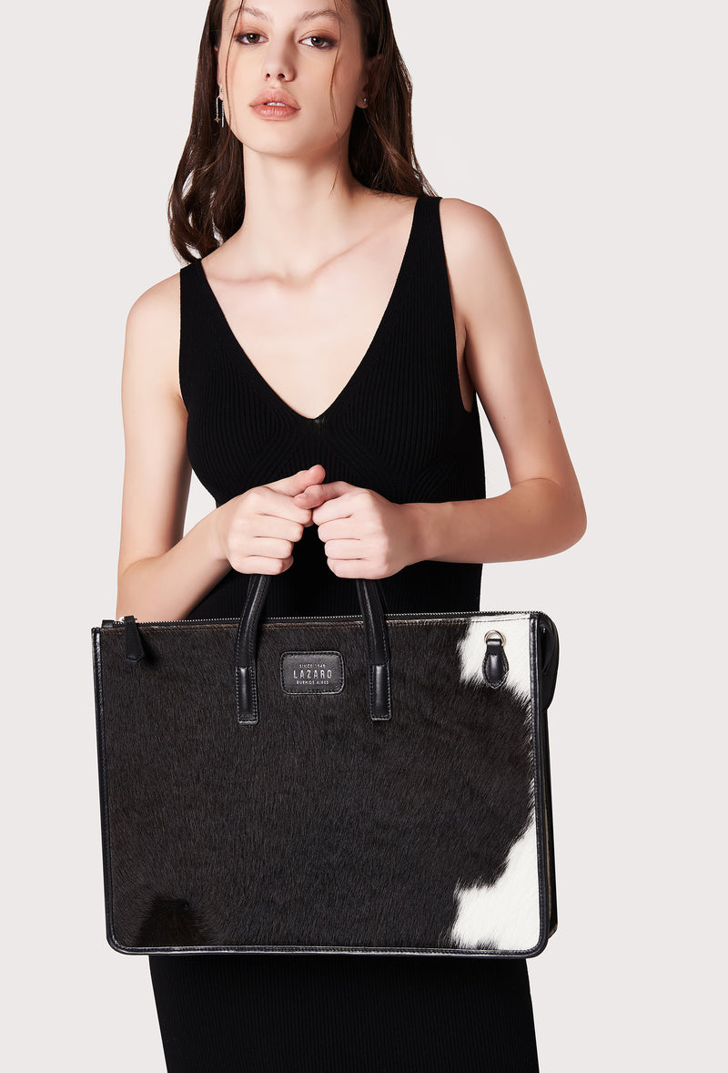A model carries a sophisticated cowhide leather slim briefcase, showcasing its sophisticated design. The bag features a detachable shoulder strap, adding to its elegant appeal. The model confidently displays the bag's size and craftsmanship while exuding a sense of style and elegance.
