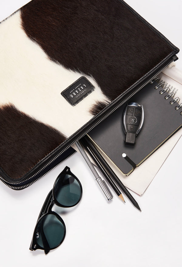 Partial photo of a Cowhide Leather Slim Computer Case that shows it can fit sunglasses, pencils and pens, notebooks, car keys and a computer.