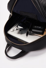 Interior of a Black Lightweight Leather Zipper Backpack that shows a zippered main compartment and an internal cell phone pocket packed with a computer, a Lazaro card holder, sunglasses, a notebook and headphones.