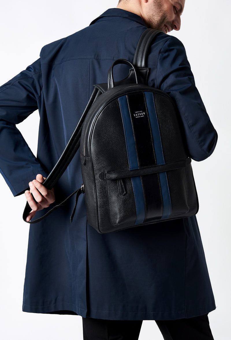 A model carries a sophisticated black lightweight leather backpack, showcasing its sophisticated design. The bag features leather trims in blue and black, external and internal multifunctional zippered pockets, adding to its elegant appeal. The model confidently displays the bag's size and craftsmanship while exuding a sense of style and elegance.
