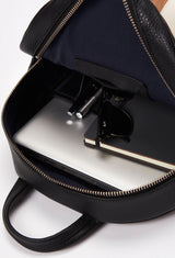 Interior of a Black Lightweight Leather Zipper Backpack that shows a zippered main compartment and an internal cell phone pocket packed with a computer, sunglasses, a notebook and pens.