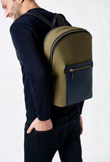 A model carries a sophisticated olive canvas and leather backpack with laptop compartment, showcasing its sophisticated design. The bag features external and internal multifunctional zippered pockets, adding to its elegant appeal. The model confidently displays the bag's size and craftsmanship while exuding a sense of style and elegance.