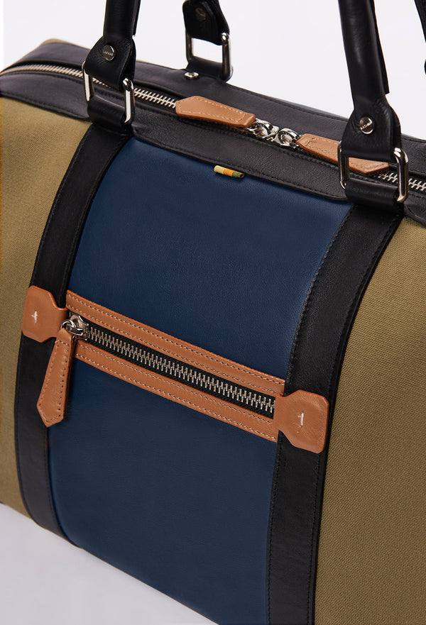 Partial photo of a Olive Canvas and Leather Duffel Bag with a blue leather strap, a zippered main compartment, a tan zippered back pocket and black leather handles.
