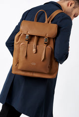 A model carries a sophisticated tan large leather backpack with buckle closure, showcasing its sophisticated design. The bag features external and internal multifunctional zippered pockets, adding to its elegant appeal. The model confidently displays the bag's size and craftsmanship while exuding a sense of style and elegance.