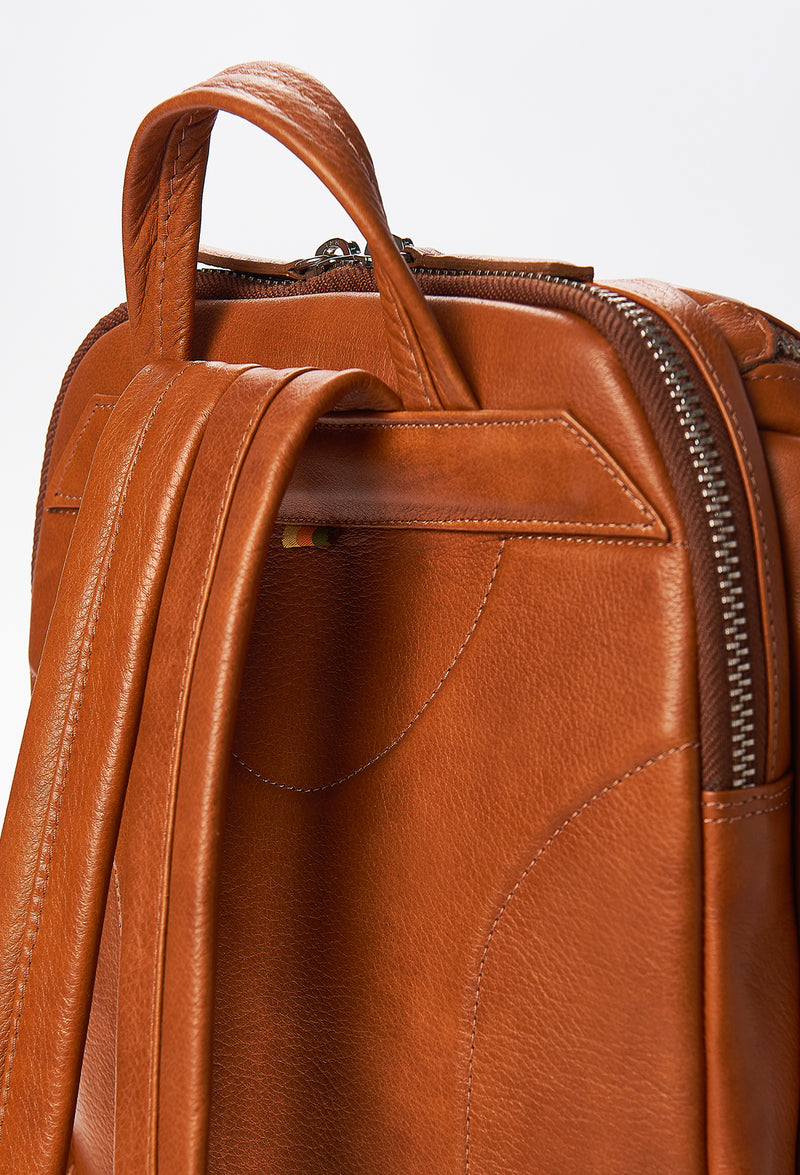 Partial photo of a Tan Leather Backpack with ergonomically shaped rear, leather padded and adjustable straps.