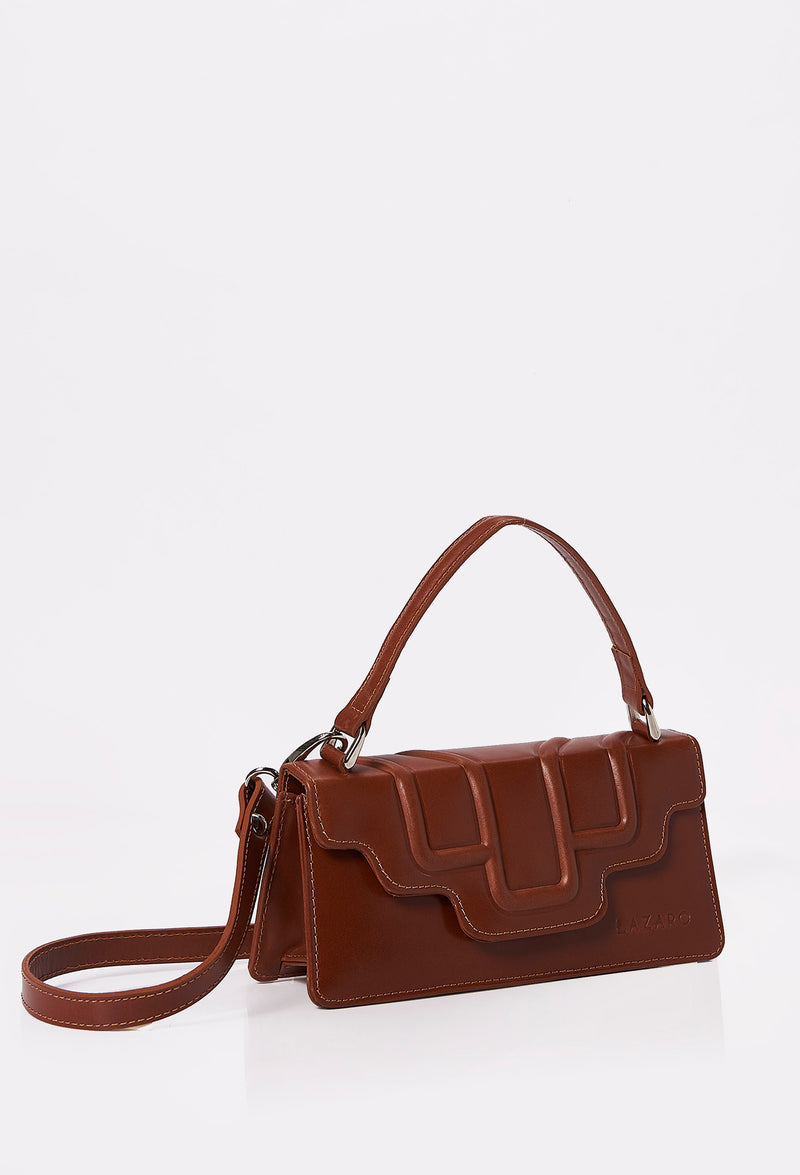 Side of a Tan Leather Crossbody Flap Bag Hilda with a raised design flap, Lazaro logo and a removable and adjustable strap.