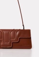 Partial photo of a Tan Leather Shoulder Flap Bag Hilda with a raised design flap and Lazaro logo.