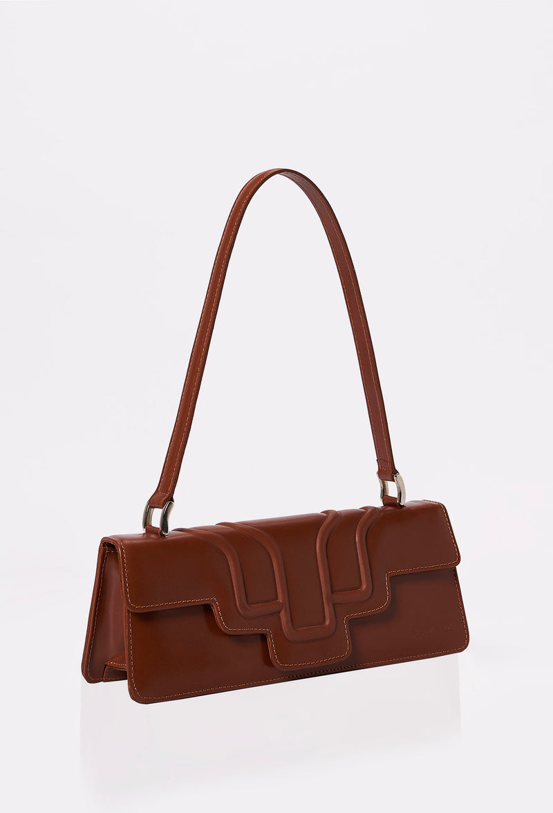 Side of a Tan Leather Shoulder Flap Bag Hilda with a raised design flap and Lazaro logo.