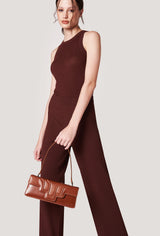 A model carries a sophisticated tan leather shoulder flap bag hilda, showcasing its sophisticated design. The bag features a raised design flap, adding to its elegant appeal. The model confidently displays the bag's size and craftsmanship while exuding a sense of style and elegance.