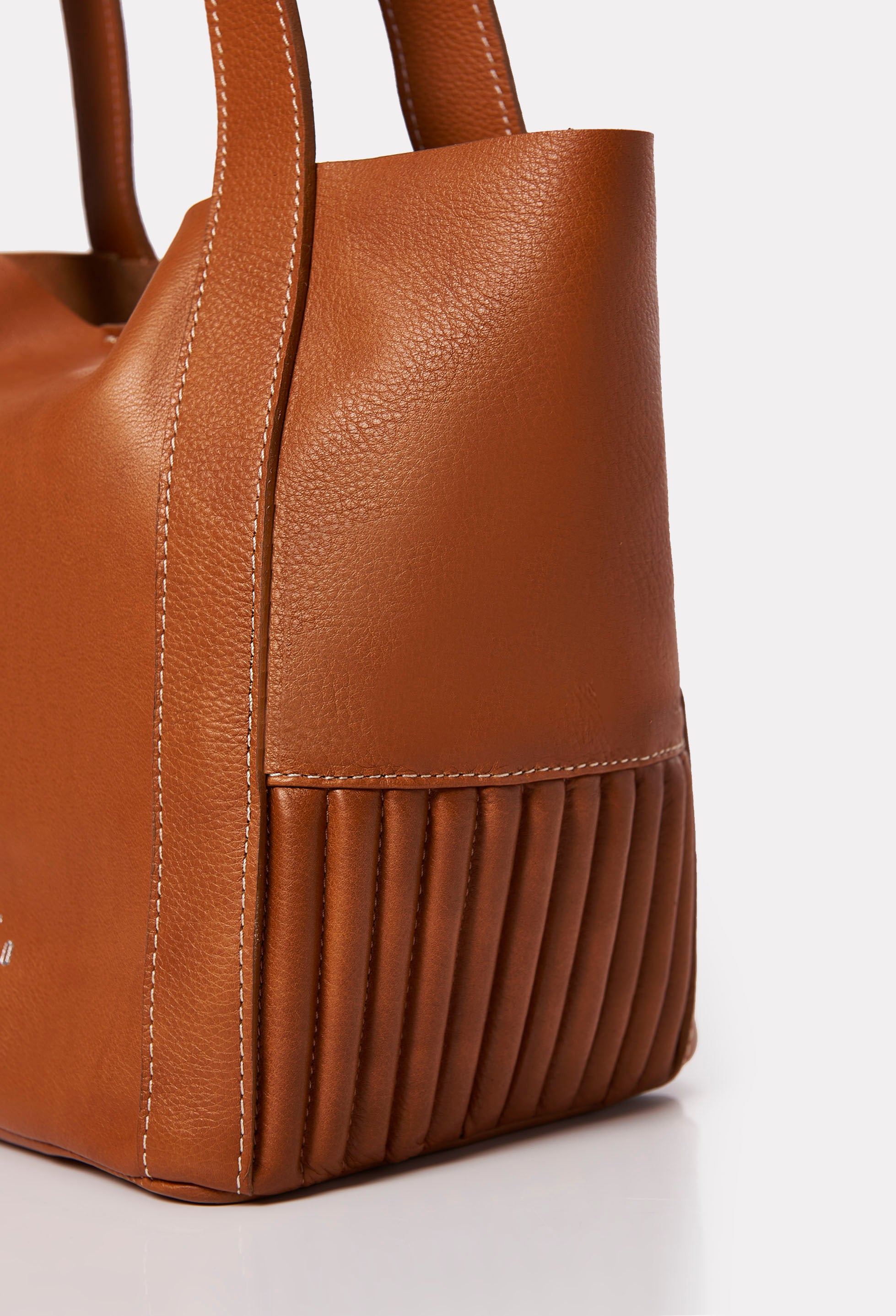 Partial photo of a Tan Leather Small
Bucket Bag Ushuaia with needlework on the sides and contrast stitching highlights.