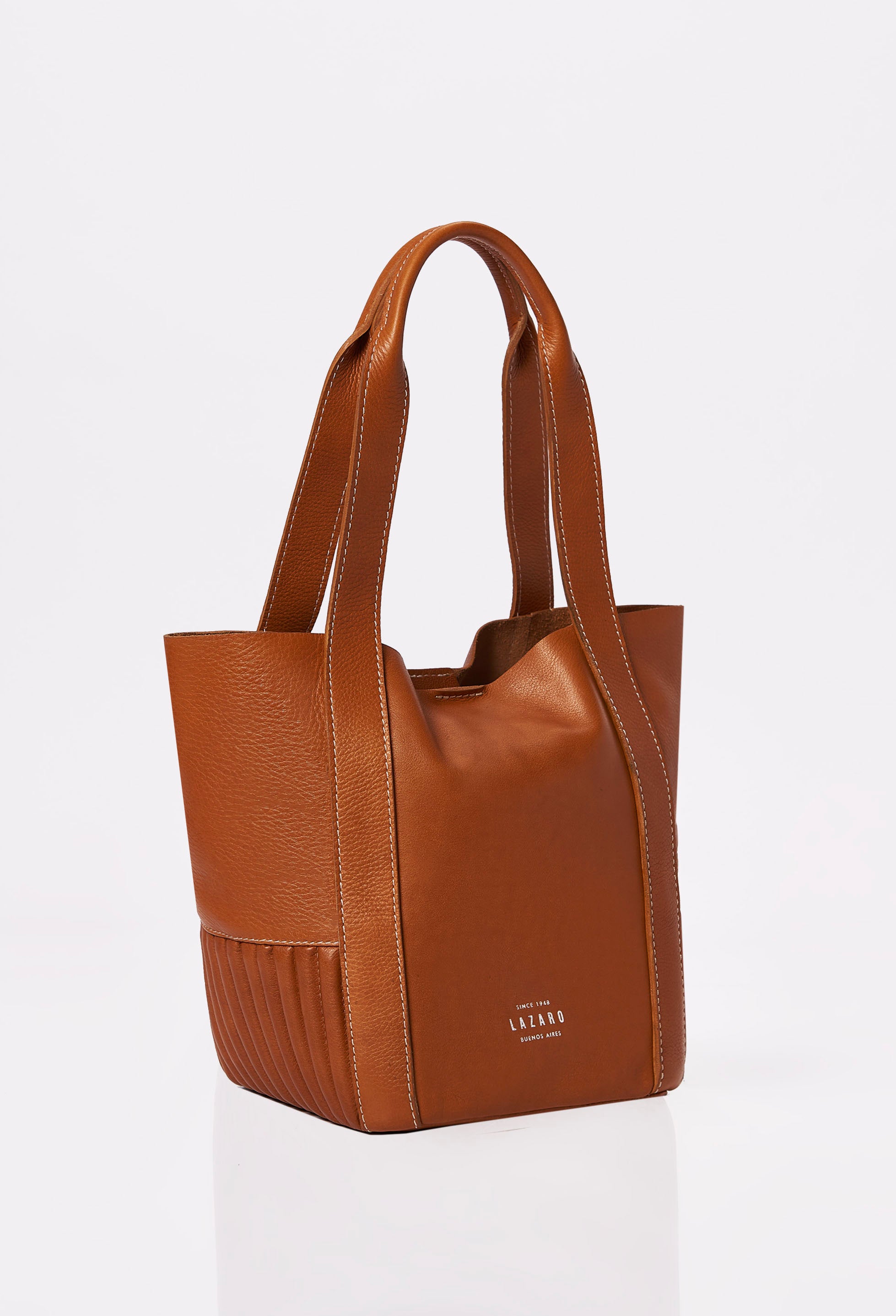 Side of a Tan Leather Small Bucket Bag Ushuaia with Lazaro logo, needlework on the sides and contrast stitching highlights.