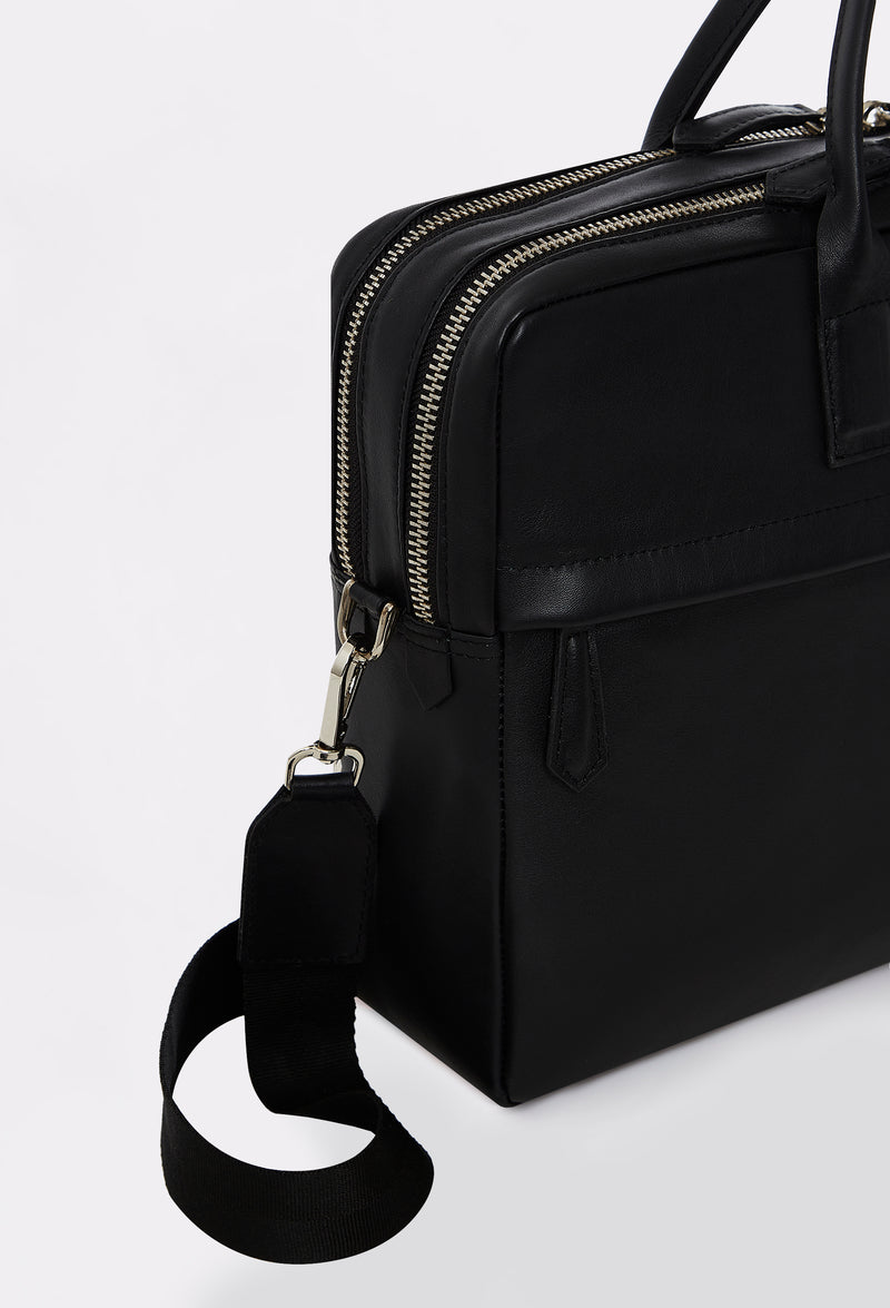 Partial photo of a Black Leather Briefcase with a shoulder strap, two zippered main compartment and a front zippered pocket.