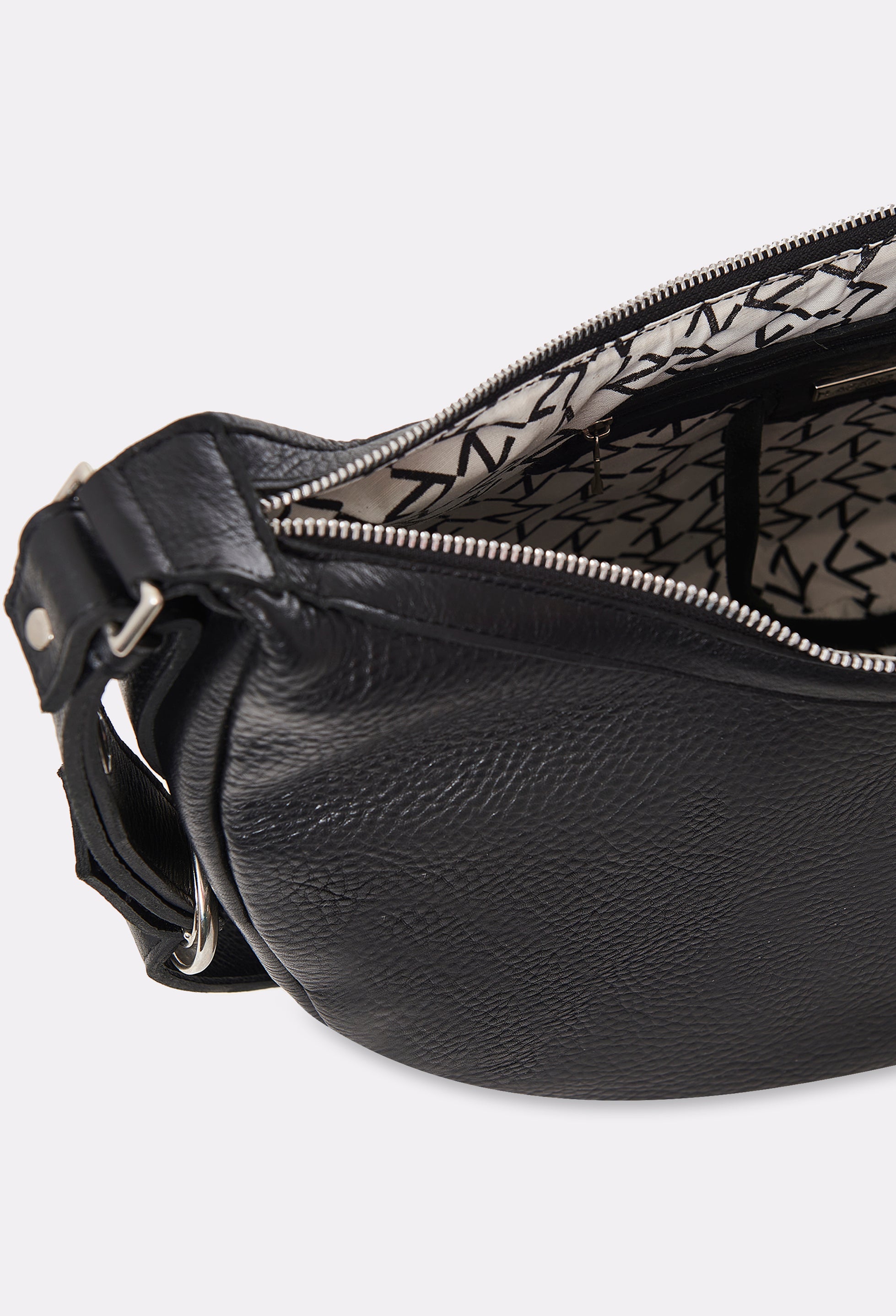Partial photo of the interior of a Black Leather Crossbody Bag Himalaya with a main zippered compartment with Lazaro patterned lining and an internal zippered pocket.