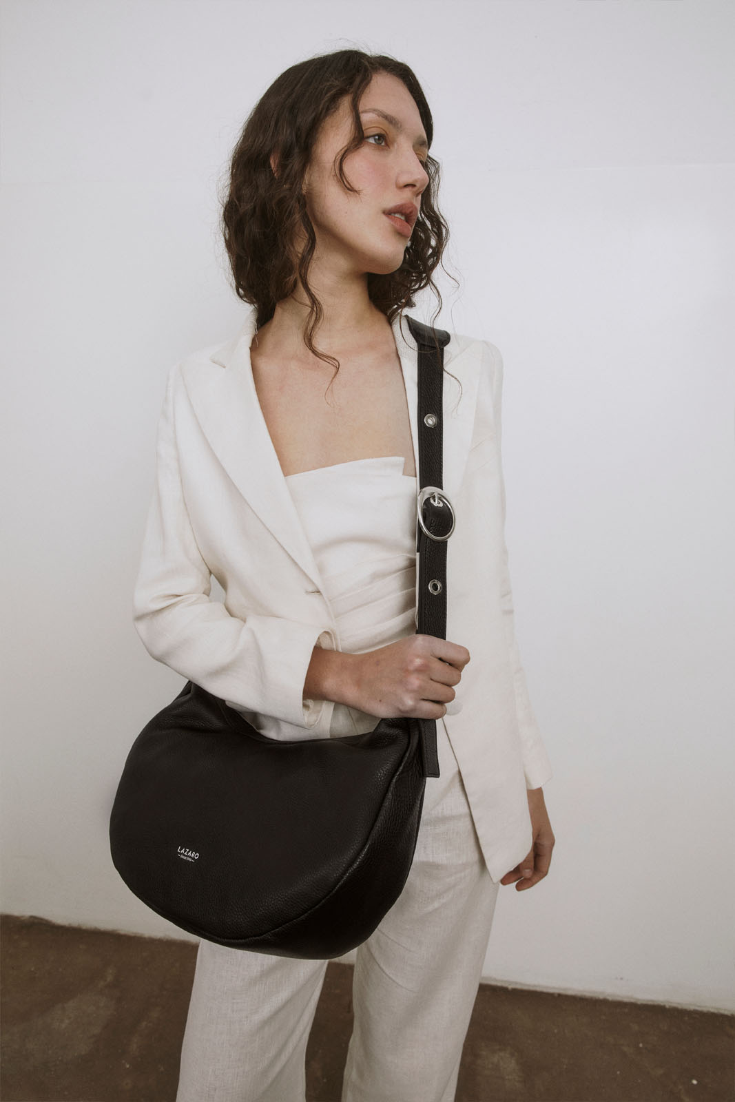 A model carries a sophisticated black leather crossbody bag, showcasing its sophisticated design. The model confidently displays the bag's size and craftsmanship while exuding a sense of style and elegance.