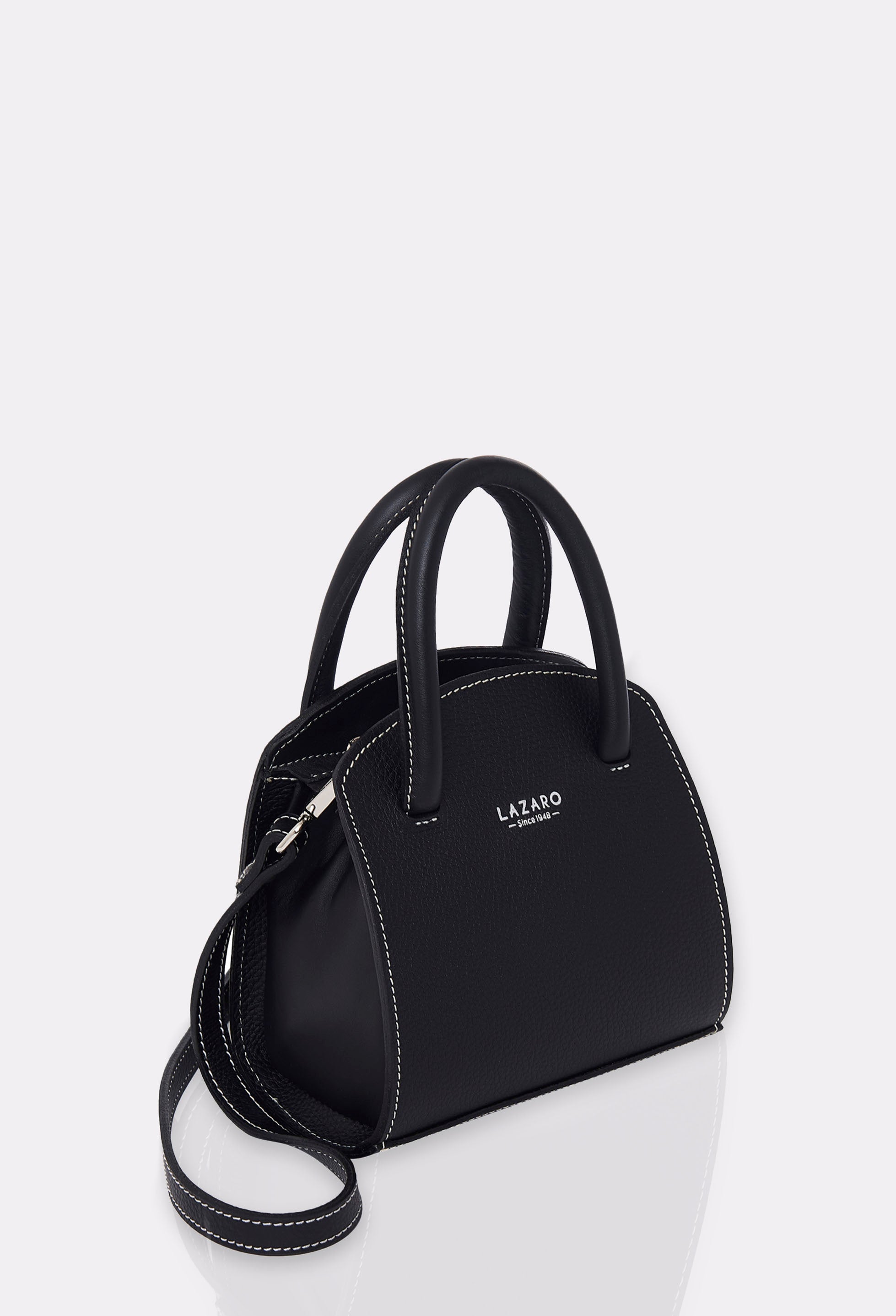 Side of a Black Leather Mini Bag Margot with a leather adjustable and detachable strap, silver embossed Lazaro logo and contrast stitching highlights.