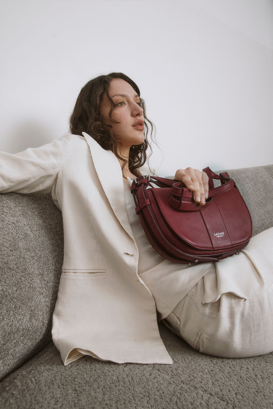 A model carries a sophisticated burgundy leather shoulder bag, showcasing its sophisticated design. The model confidently displays the bag's size and craftsmanship while exuding a sense of style and elegance.