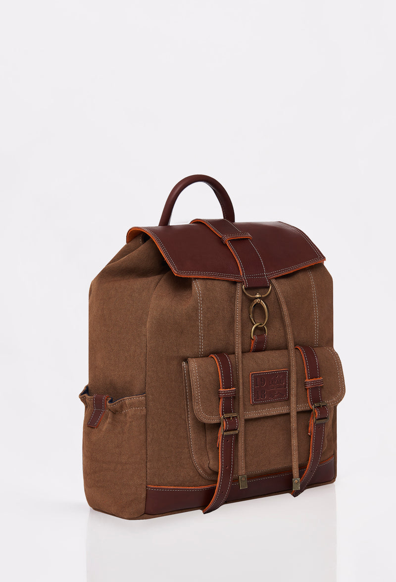 Side of a Coffee Canvas Backpack with Lazaro logo, distressed antiqued bronze fittings and leather details.
