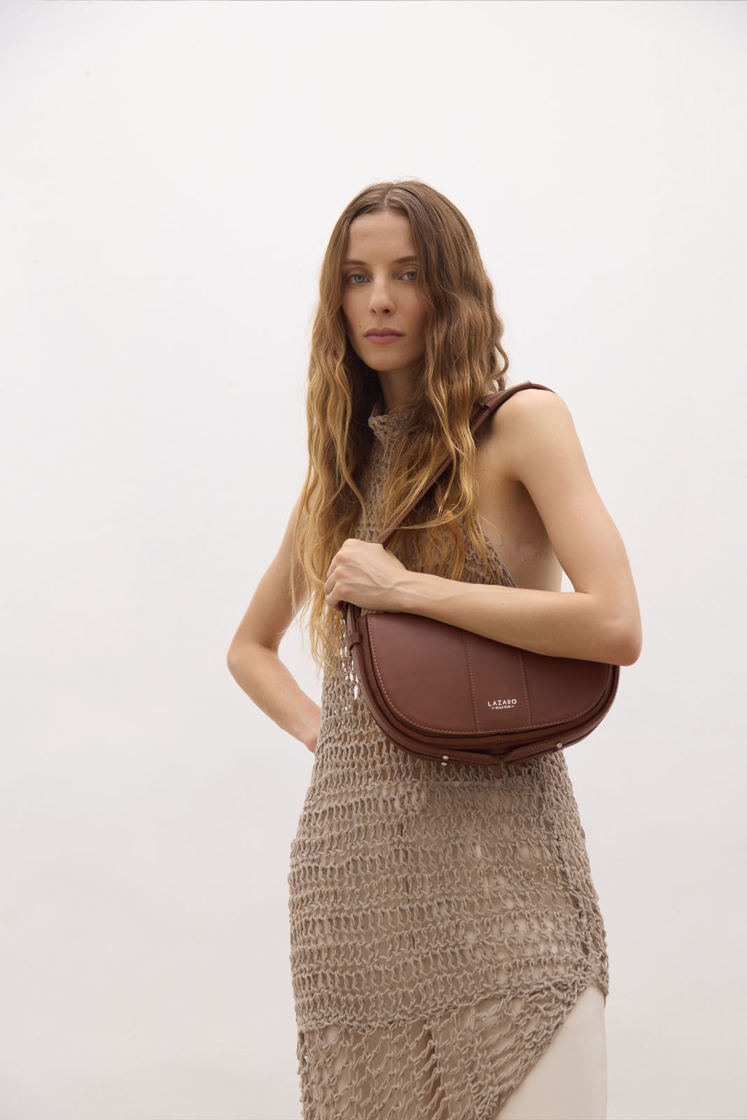 A model carries a sophisticated cognac leather shoulder bag, showcasing its sophisticated design. The model confidently displays the bag's size and craftsmanship while exuding a sense of style and elegance.