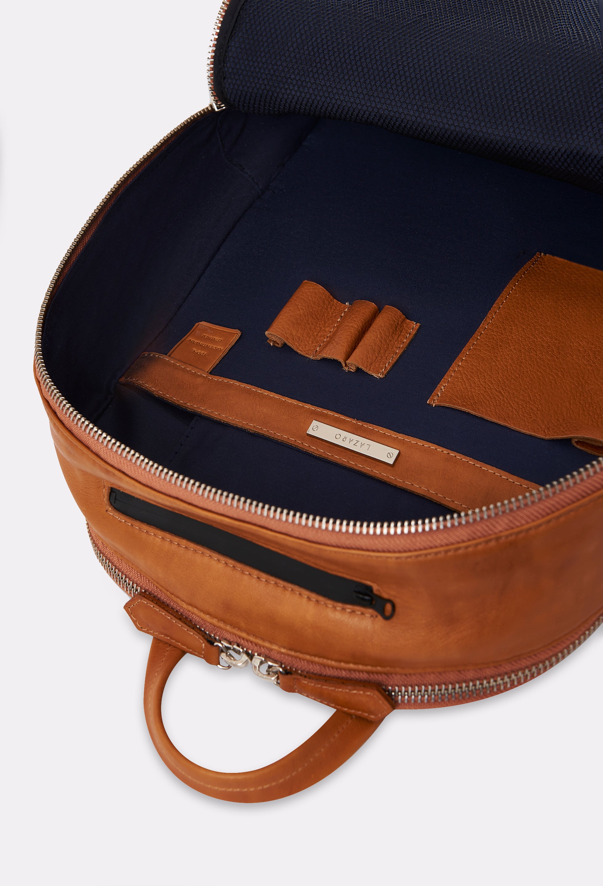 Interior of a Tan Leather Backpack that shows two zippered main compartments, with an internal cell phone pocket, pen holders and multifunctional pockets.