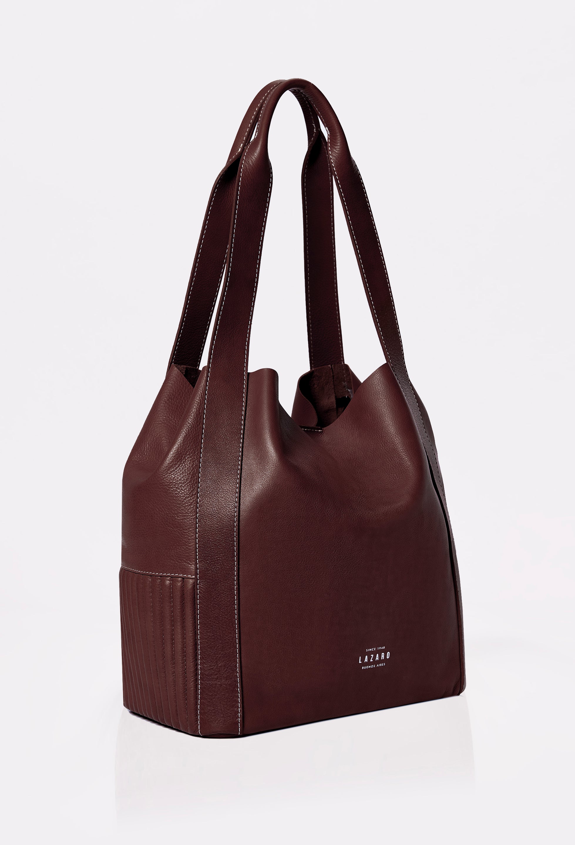 Side of a Large Leather Bucket Bag Ushuaia Coffee with Lazaro logo, needlework on the sides and contrast stitching highlights.