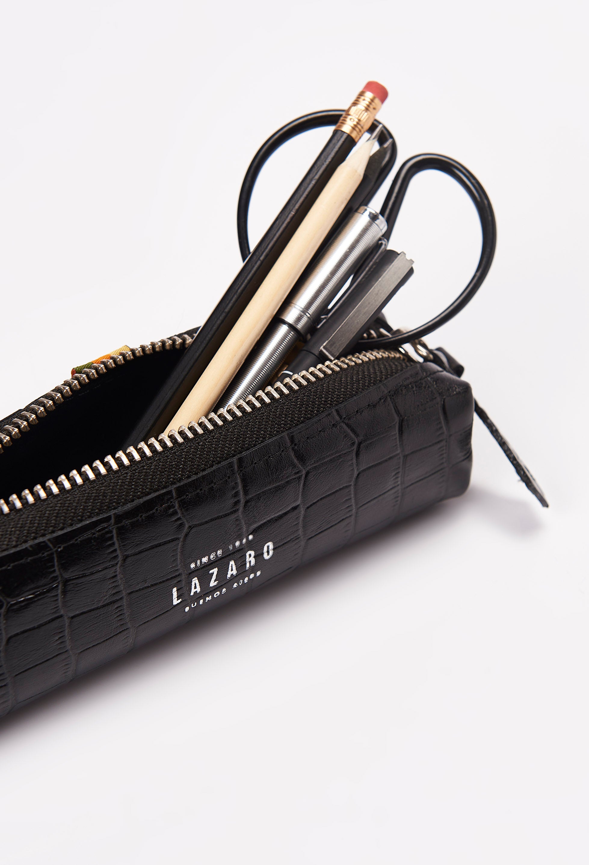 Interior of a Black Croco Leather Pencil Case packed with pens, pencils and a scissor.