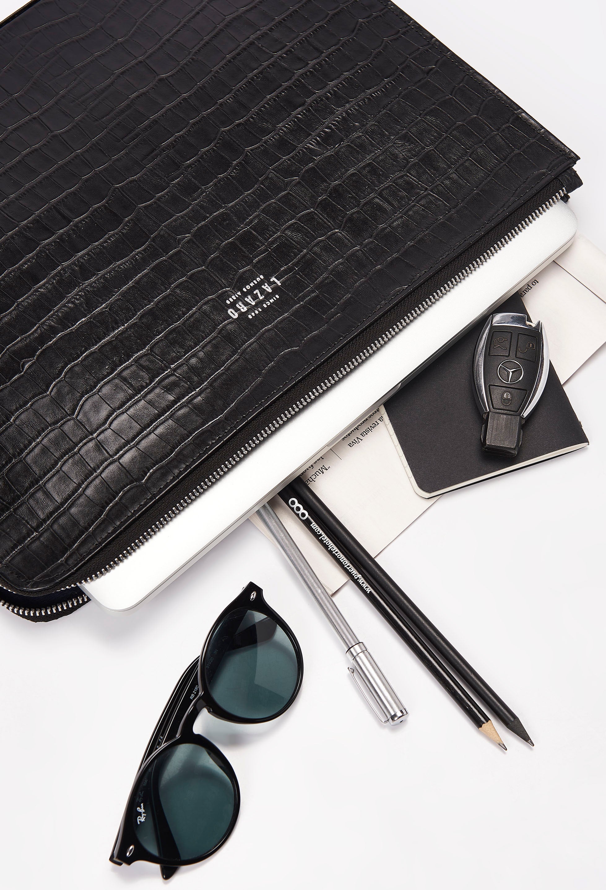 Partial photo of a Black Croco Leather Slim Computer Case that shows it can fit sunglasses, pencils and pens, notebooks, car keys and a computer.
