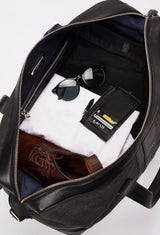 Interior of a Black Large Canvas Duffel Bag packed with a Lazaro cardholder, clothes, sunglasses and a pair of shoes.