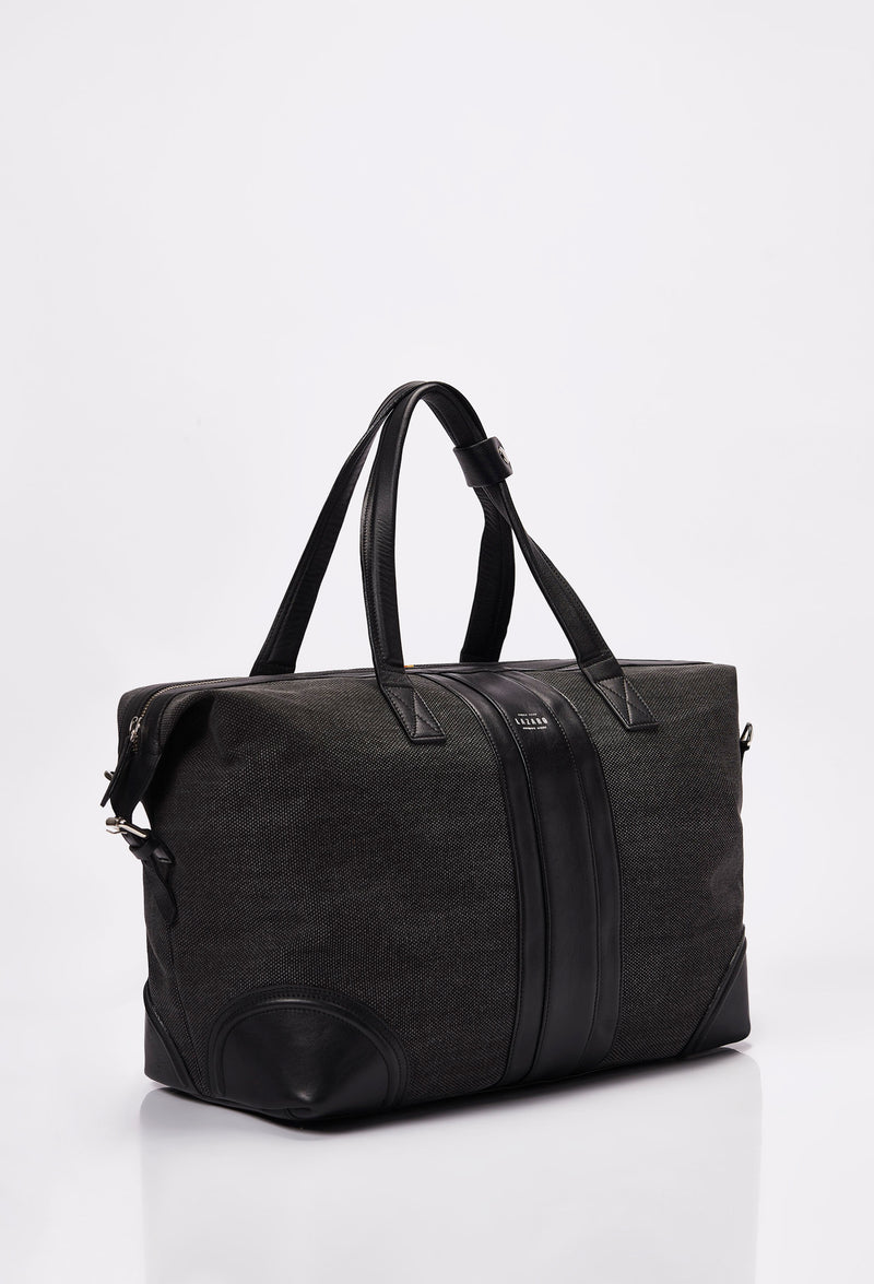 Side of a Black Large Canvas Duffel Bag with Lazaro logo, leather stripes and handles.