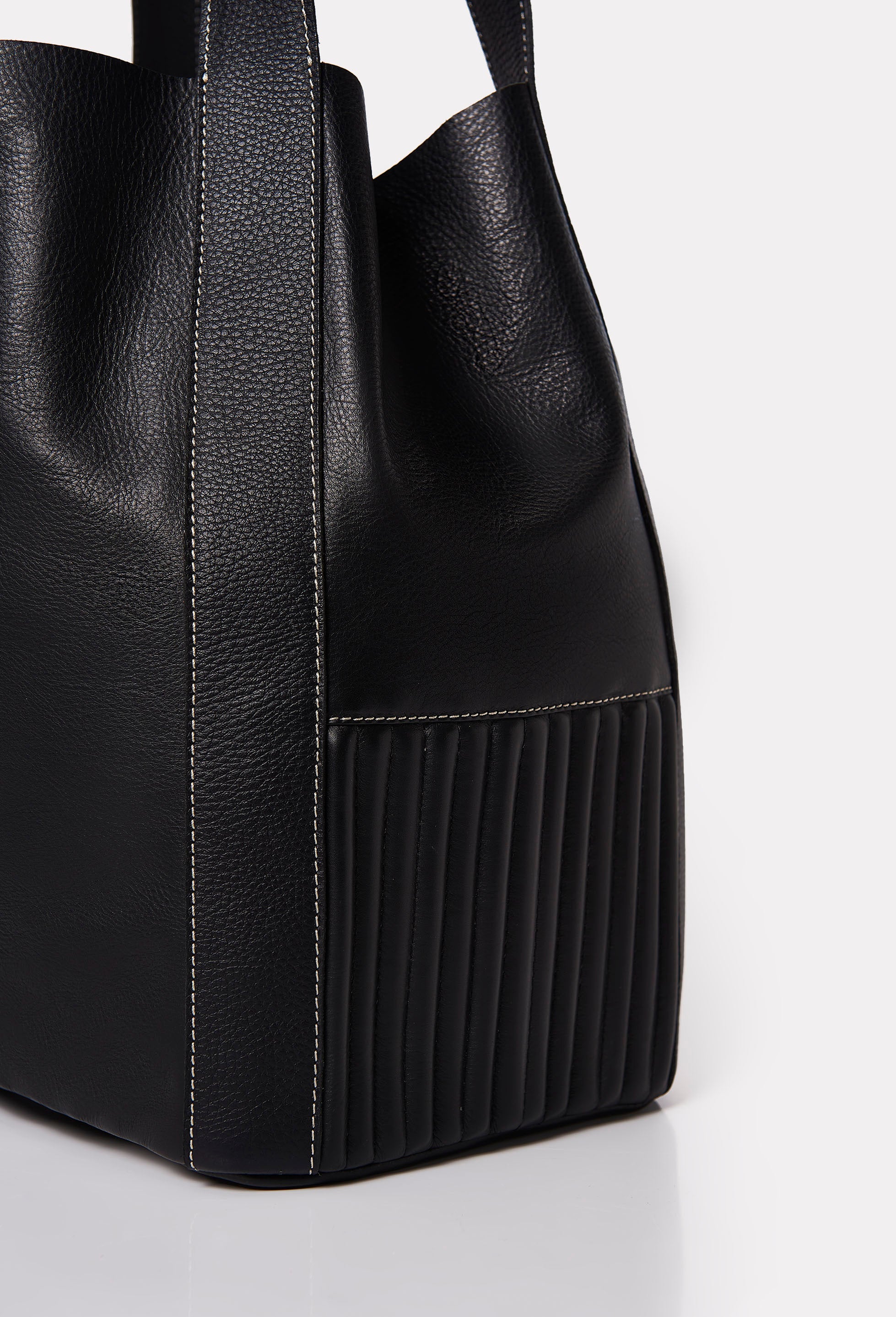 Partial photo of a Black Leather Bucket Bag Ushuaia with needlework on the sides and contrast stitching highlights.