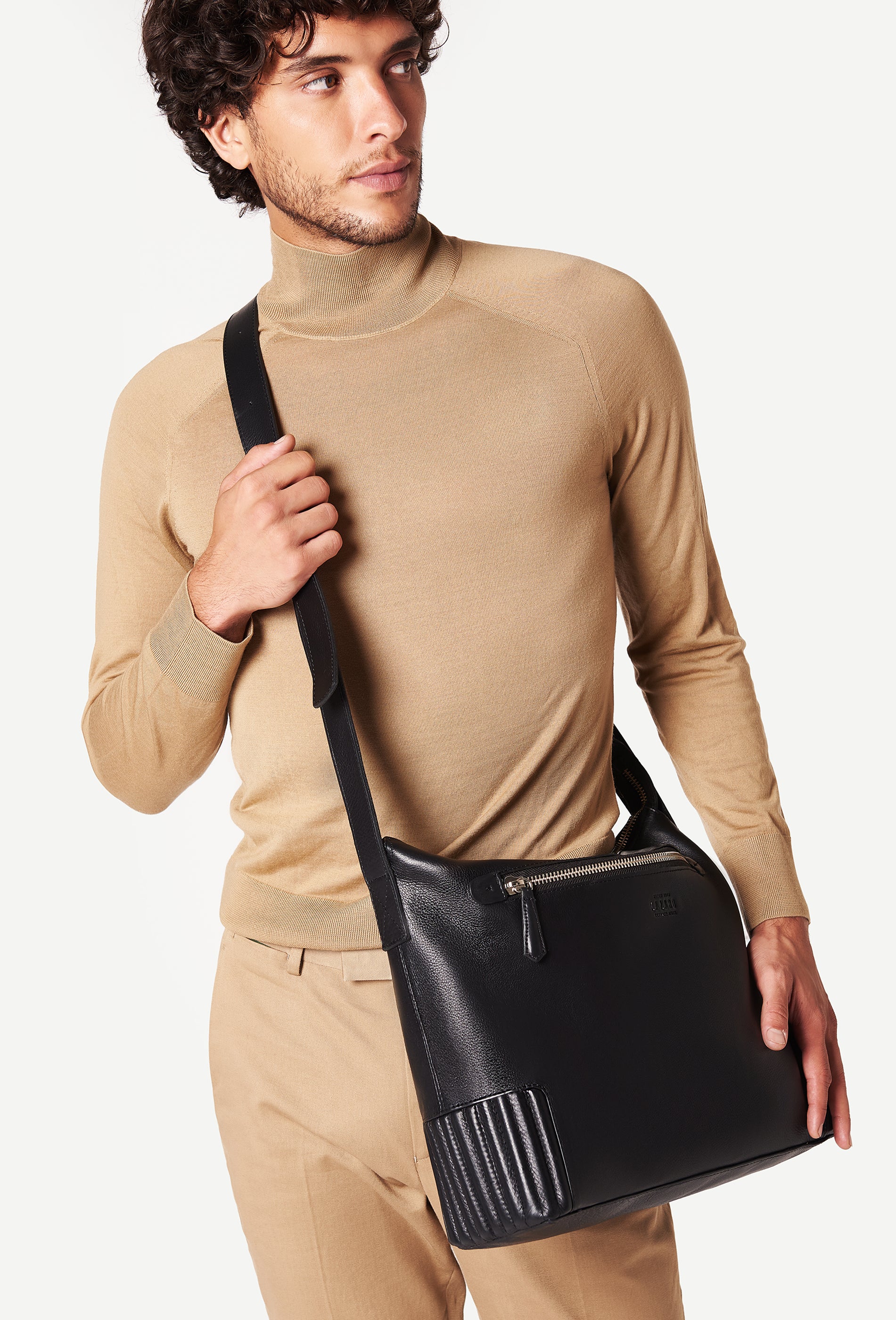 A model carries a sophisticated black leather crossbody messenger, showcasing its sophisticated design. The bag features unique needlework on its side, adding to its elegant appeal. The model confidently displays the bag's size and craftsmanship while exuding a sense of style and elegance.